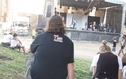 <p>Mężczyzna siedzi w czarnej koszulce SLOT Art Festival i patrzy na scenę</p>